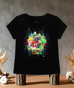 This black tee is packed with bold colors and playful energy, it features four of the most iconic characters from the Nintendo universe. it is on wooden blocks on a table for display.